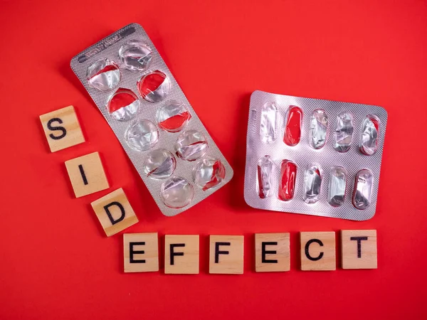 Words side effect on colored red paper texture background. Concept. Empty pill blister pack. Covid 19 illness therapy. Disease treatment side effect or toxicity. Copy space. Mock up design template