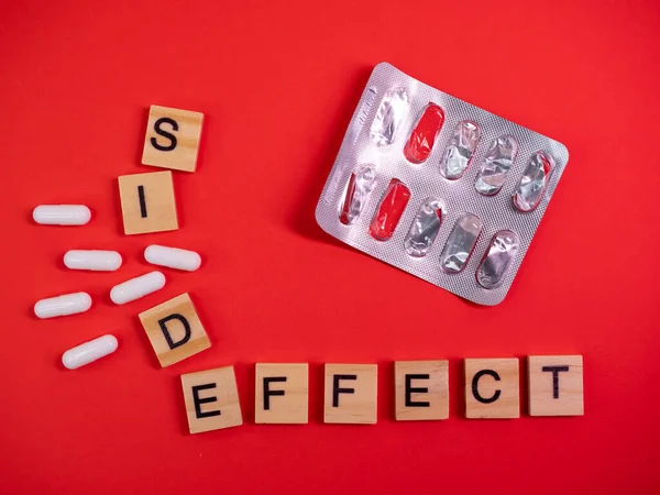 Words side effect on colored red paper texture background. Concept. Empty pill blister pack. Covid 19 illness therapy. Disease treatment side effect or toxicity. Copy space. Mock up design template