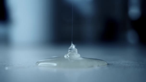 Thick liquid glue slowly pours in thin stream from above and spreads on surface — Vídeo de Stock