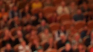 Unrecognizable out of focus spectators in hall intense applaud while sitting