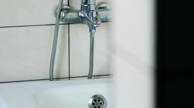 Wall-mounted shower and bathtub. Bathroom with white tiled walls. Hotel toilet