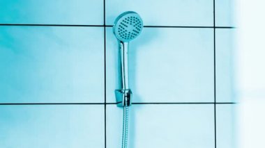 Wall-mounted shower and bathtub. Bathroom with white tiled walls. Hotel toilet