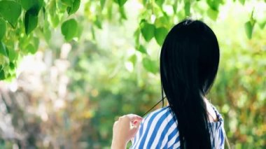 Beautiful happy young woman in love walks among green leaves on birch branches