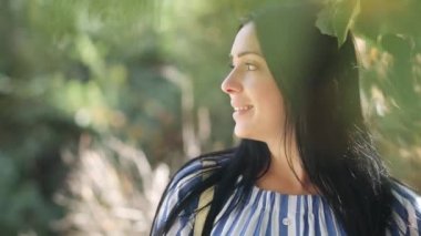Beautiful happy young woman in love walks among green leaves on birch branches