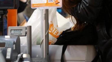 Müşteri süpermarketteki kasada ödeme yapıyor. Bayan eşyaları çantaya koyar.