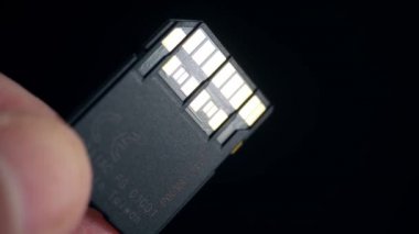 Ultra yüksek hızlı UHS II SD kart parmakları koyu arkaplanda. Makro yakın plan