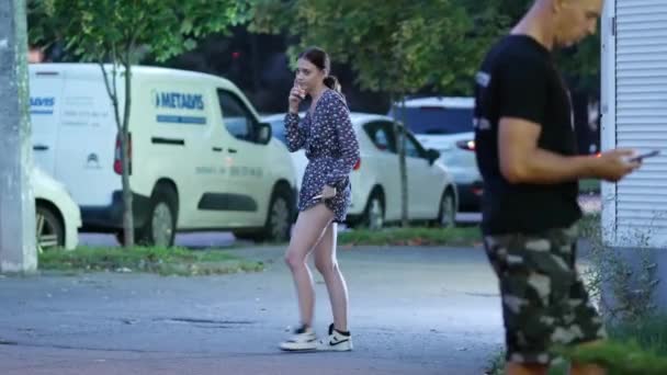 Ein Mädchen in kurzen Hosen und heller Bluse raucht auf der Straße eine elektronische Zigarette — Stockvideo
