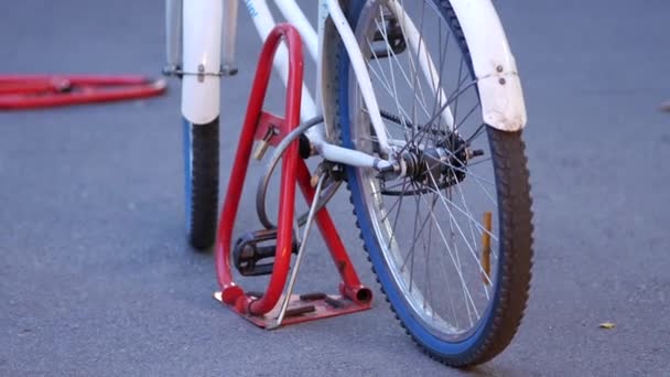 Vélo blanc pour femmes se tient sur le trottoir et est attaché à un dispositif anti-stationnement — Video