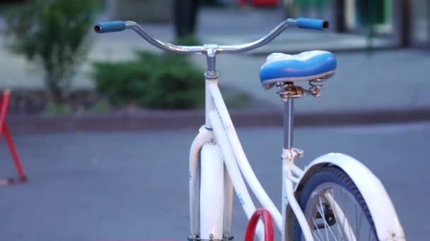 Bílé ženy kolo stojí na chodníku a je připoután k anti-parkovací zařízení — Stock video