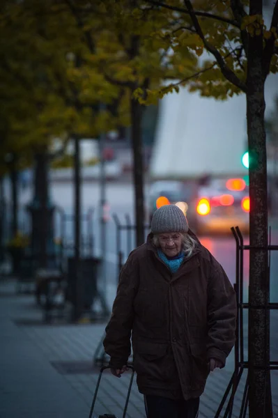 VILNIUS, LITVÁNIA - OKTÓBER 6 2021: Este egy nagymama egy vizsgálókocsival sétál végig az utcán — Stock Fotó