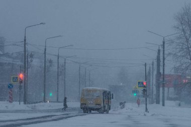 ARKHANGELSK, RUSSIA - HAZİRAN 05 2022: Sarı bir otobüs kar altında kentten geçiyor