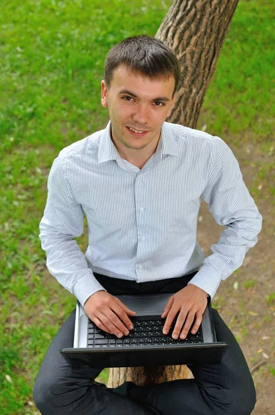 Dışarıda dizüstü bilgisayar kullanan gülümseyen bir adam.. — Stok fotoğraf