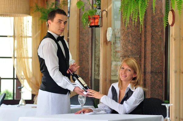El camarero del restaurante ofrece al visitante vino Imagen De Stock