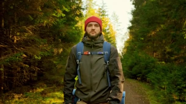 Pomalý pohyb Portrét Aktivní zdravý kavkazský turista s batohem Procházky ve slunečním dřevě. Muž Cestovatel s procházkami po lese, volný čas, bio-turistika. Mladý muž pěší turistika v lese na podzim. — Stock video