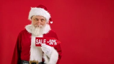 Noel Baba 'nın imzası indirimli -50 dolar indirimli, parmağını boş bir yere doğrultuyor ve Kırmızı Arkaplanda İndirime ve Gülümsemeye Bakıyor. Büyük İndirim, Noel Tatil Satışı