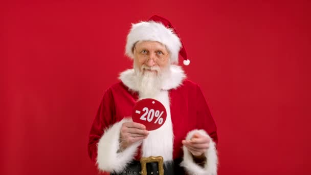 Happy Smiling Santa Claus Δείχνει στα χέρια του ένα διαφημιστικό banner με διαφορετική έκπτωση, διαφορετικό ποσοστό των εκπτώσεων για πώληση σε κόκκινο φόντο. Χριστουγεννιάτικες εκπτώσεις για το νέο έτος Μαύρη Παρασκευή. — Αρχείο Βίντεο