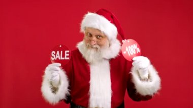 Noel indirimi -100. Neşeli Noel Baba Noel Satışı 'ndan Dans Ediyor ve Neşelidir. Üzerinde yazı olan iki pankart ve Kırmızı Arkaplan' da Kameraya Yazıtlar Göstererek Hava Alıyor..