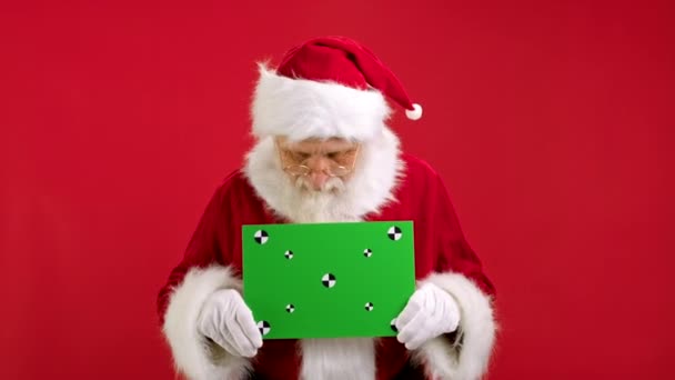 快乐的圣诞老人为银行家做广告，用跟踪站起来，看着绿色的旗帜，愉快地摇头。为你的文字刊登绿屏广告. — 图库视频影像