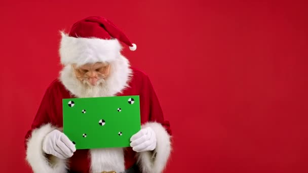 Vrolijke Kerstman Holding Green Screen Banner Tracking Points voor Copy Space. Blanco groen scherm. Toont een goedkeurende duim-up gebaar met ruimte voor tekst of reclame op rode achtergrond. — Stockvideo
