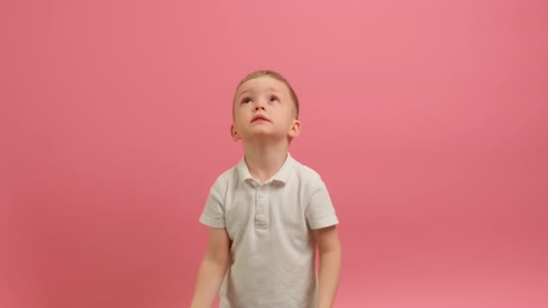 Blond Boy vomita Confetti rojo en forma de corazones, sonrisas y trata de atrapar el corazón con sus manos en el fondo amarillo. Slow Motion Video Boy celebra el Día de San Valentín en Confetti de Corazones. — Vídeo de stock