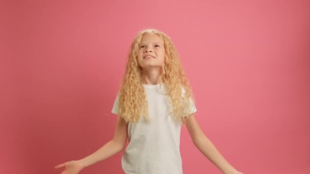 Happy excited blonde girl smiles and enjoys rain of red confetti in form of hearts on pink background. Slow motion concept of happiness, partying, winning, celebrating Valentines Day or Mothers Day. — стокове відео