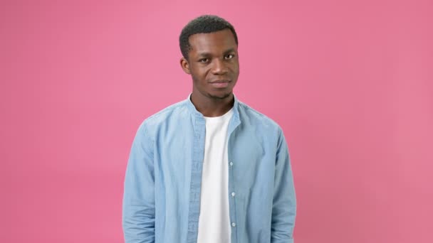 Black young African American guy suffers from depression and fatigue from an overloaded brain, covers his head with his hands and screams in pain against pink background. Panic attack, stress at work. — ストック動画