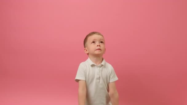 Slow Motion Video Boy Sevgililer Gününü Kupa Konfeti 'sinde kutluyor. Sarışın çocuk, elleri sarı arka planda kırmızı konfeti kusar, kalp şeklinde gülümser ve kalbi yakalamaya çalışır.. — Stok video