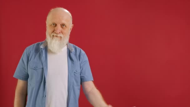 Old bearded man Holds Sign With Inscription Sale -30 off, Points His Finger at Empty Space Mock up and Looks at Discount in Camera and Smiles on Red Background. Μεγάλες εκπτώσεις τις μαύρες Παρασκευές. — Αρχείο Βίντεο