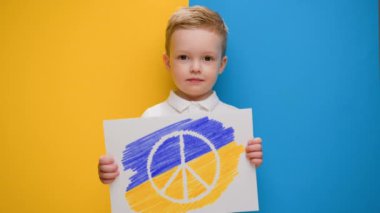 Pasifist çocuk Ukrayna 'daki savaşı protesto ediyor. Ukrayna bayrağının sarı-mavi arka planında gülümseyen sarı saçlı çocuk savaş karşıtı Pasifik hareketinin logosuyla bayrak tutuyor..