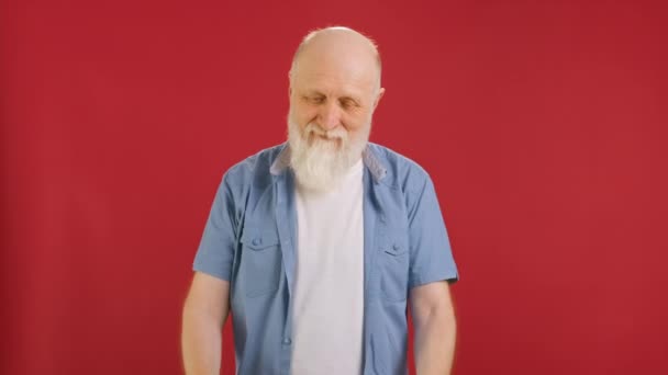 Happy old man holding Banner with Green Screen Tracks Points for Copy Space. Empty Green Screen Board. waves Head approvingly, approves of choice With Space for Text or Advertising on red Background. — Video