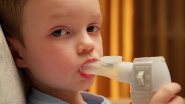 Portrait caucasian child with asthma problems inhales with tube in his mouth. Treatment of pneumonia with nebulizer at home. Child has respiratory infection or bronchitis, and he is breathing heavily. — Vídeos de Stock