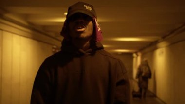 Russia - February 17 2022: Black singer reads rapping while looking at camera, gesticulating with his hands in underground subway. Portrait African-American rapper singing song rap in lot of people.