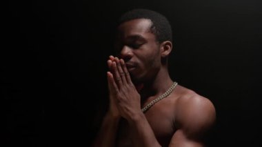 Portrait young guy looking into camera to cameraman and holding his arms folded in front of him. Slow motion shot serious looking African-American man. Piercing look, look of dependability. calm.