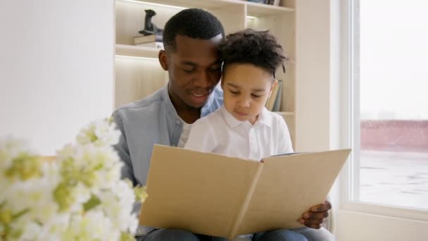 Family African Americans, father and 3-year-old son read book, father teaches his son to read letters. Black skin father reads book to his young son, family education, family pastime. — Stockvideo