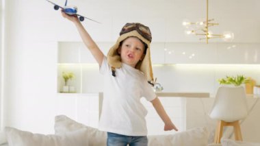 Cute 4 year old caucasian child in glasses and pilot hat plays at home with toy modern airplane, child dream of becoming pilot, thirst for travel, tourism and air travel. Kid play air craft toy home.