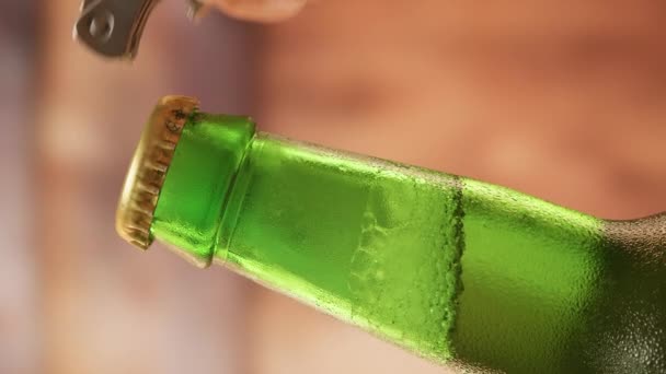 Close-up caucasian man hand opens lid fresh light beer in green bottle with lid opener on blurry studio background. Slow-motion video of light lager is opened with the help of bottle opener. — Stockvideo