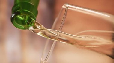 Close-up of light fresh beer pouring into glass. Vertical video of beer being poured into beer glass in slow motion. Light beer lager foams and pours from bottle into glass.