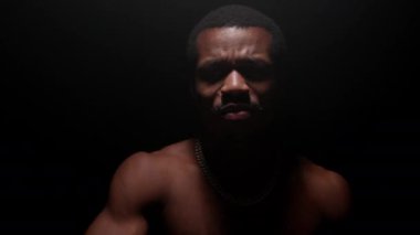 Shooting clip of rap artist. Man sings rapping song. Handsome black African American man with pumped naked torso sings song emotionally waving his arms on black background