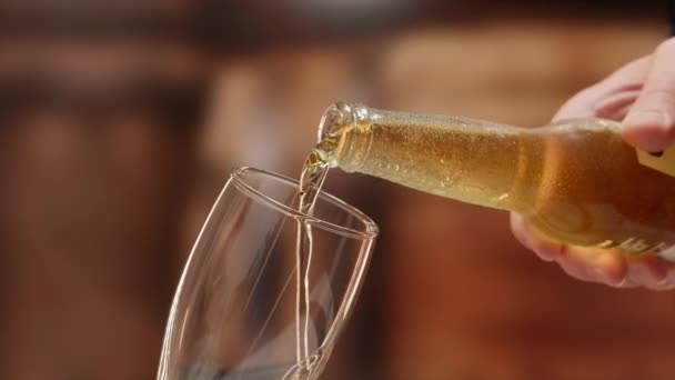 Close-up light fresh beer poured into glass steamed up from cold. Beer is poured from glass bottle into beer glass in slow motion. Lager beer foams and pours from bottle into glass. — Video Stock