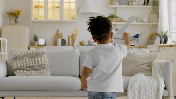 Kid aspires to fly high in clouds while playing with an airplane. African-American child in aviapilot glasses holds toy airplane in his hands, circles with the plane and dreams of flying in clouds. — Vídeo de stock