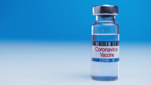 Victory over a worldwide epidemic nCoV. Found a cure for virus sars-cov-2. Medical ampoule with coronavirus covid-19 vaccine on blue background. — Stock Video