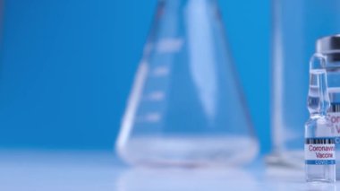 Close-up ampoules with COVID-19 coronavirus vaccine. Bottle of vaccine against SARS-CoV-2 virus on background laboratory table. Drugs against nCoV pandemic. Concept defeating coronavirus