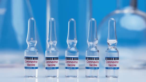 Butelka szczepionki przeciwko wirusowi SARS-CoV-2 na stole laboratoryjnym. Ampułki zbliżeniowe ze szczepionką przeciw koronawirusowi COVID-19. Leki przeciwko pandemii nCoV. Koncepcja zwalczania koronawirusu — Wideo stockowe