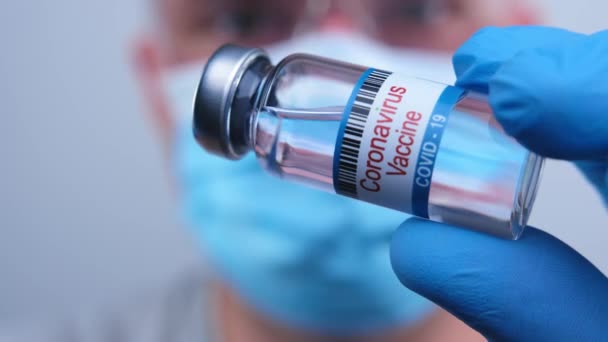 Doctor in mask dials a coronavirus vaccine into a syringe to vaccinate against a worldwide epidemic sars-cov-2. Pharmacology drugs against pandemic nCoV. Concept victory over coronavirus 2019-ncov. — Vídeo de Stock