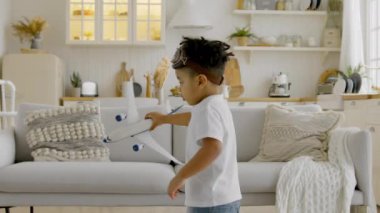 African-American child in aviapilot glasses holds plane in his hands, circles with plane and dreams of flying in clouds. Kid is playing in Crash of an airplane. Plane crashes to ground