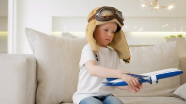 Portrait 4 year old caucasian child in glasses and pilot hat plays at home with toy modern airplane, child dream of becoming pilot, thirst for travel, tourism and air travel. Kid play air craft toy