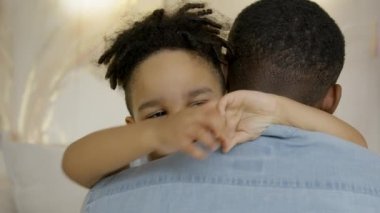 Happy hugs of family of father and son, friendship in family of child and dad. Relationships in family, love hugs. Happy 3 year old mixed race kid hugging black skin african american father