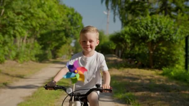 Cute Child Rides Bicycle Colorful Windmill Toy Happy Smiling Blond — Stockvideo