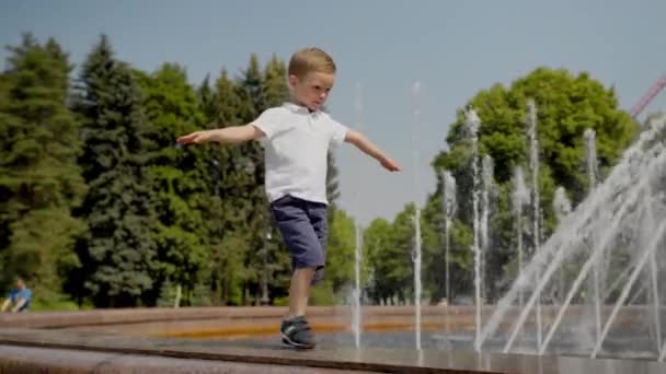 Little Boy Walks Carefully Barrier Fountain Raised Hands Blond Child — Stockvideo