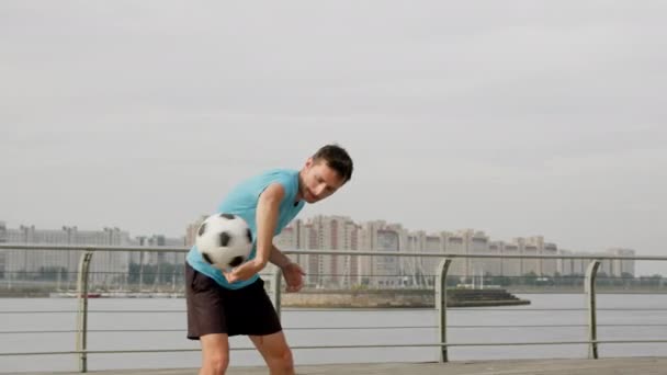 Young Sportsman Balances Ball City Buildings Freestyler Wearing Blue Shirt — Video Stock